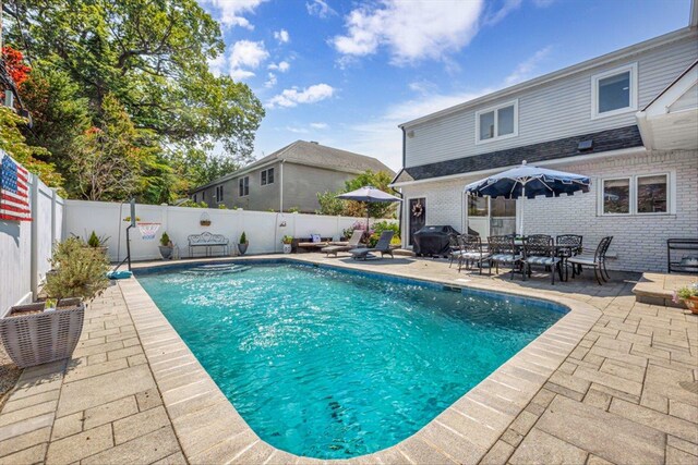 view of swimming pool featuring area for grilling, a patio area, a fenced in pool, and a fenced backyard