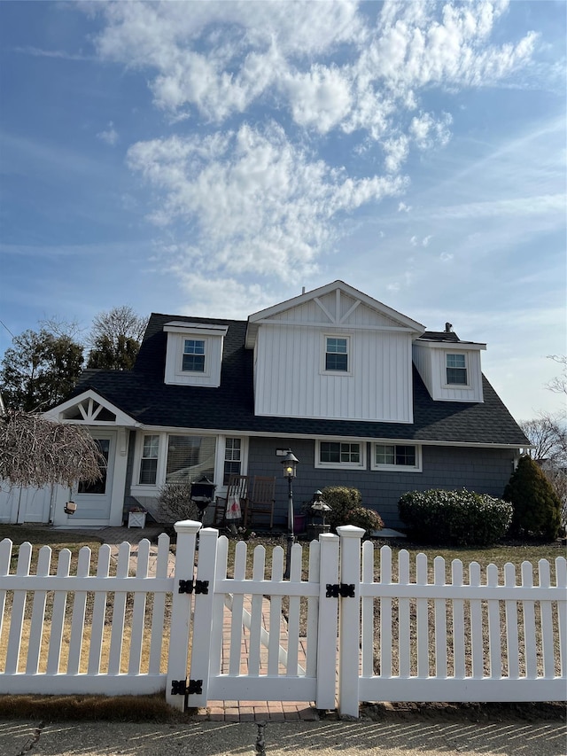 view of front facade with a fenced front yard and roof with shingles