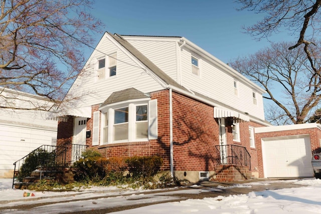 view of snow covered exterior with a garage and brick siding