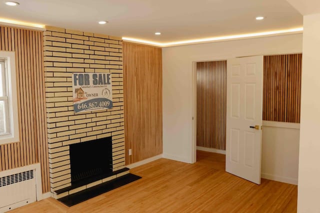 unfurnished living room with recessed lighting, radiator, wood finished floors, and a fireplace