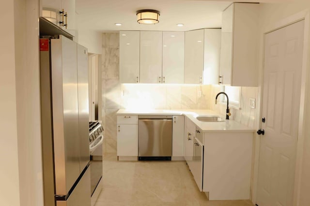 kitchen with tasteful backsplash, a sink, appliances with stainless steel finishes, white cabinetry, and modern cabinets