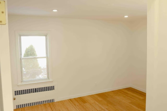 unfurnished room with recessed lighting, radiator, baseboards, and wood finished floors