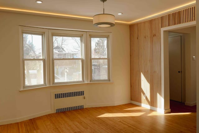 spare room with recessed lighting, radiator, baseboards, and wood finished floors