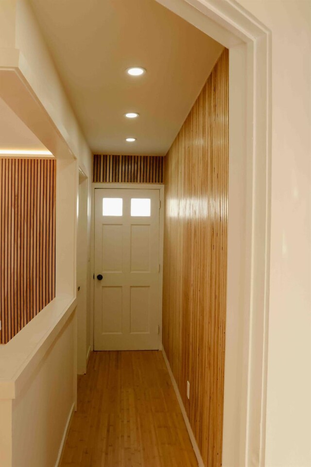 corridor featuring wooden walls, recessed lighting, and light wood-type flooring