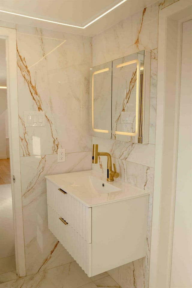 bathroom featuring marble finish floor, vanity, and tile walls