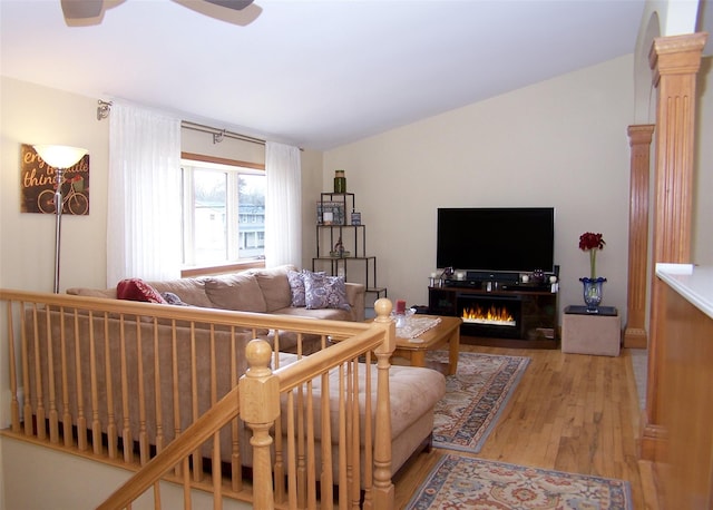 living area with wood finished floors, a ceiling fan, and vaulted ceiling