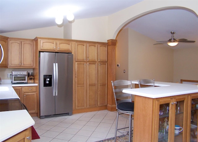 kitchen featuring light tile patterned flooring, stainless steel fridge with ice dispenser, arched walkways, ceiling fan, and vaulted ceiling