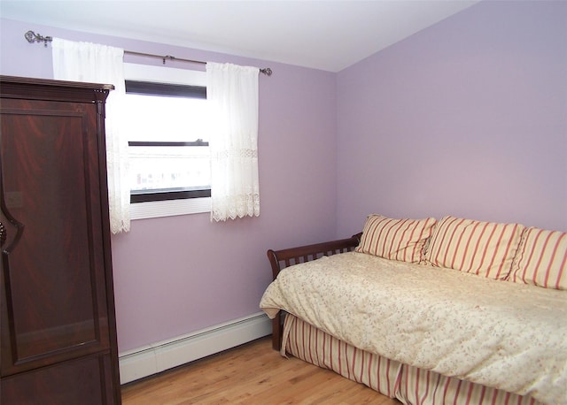 bedroom with a baseboard heating unit and light wood-type flooring