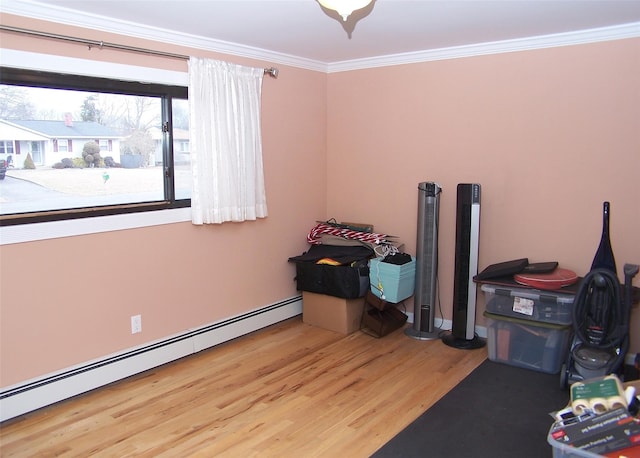 interior space featuring baseboard heating, wood finished floors, and crown molding