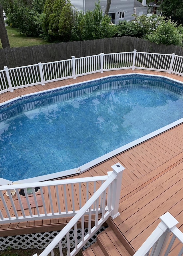 view of swimming pool featuring a fenced in pool, a deck, and fence