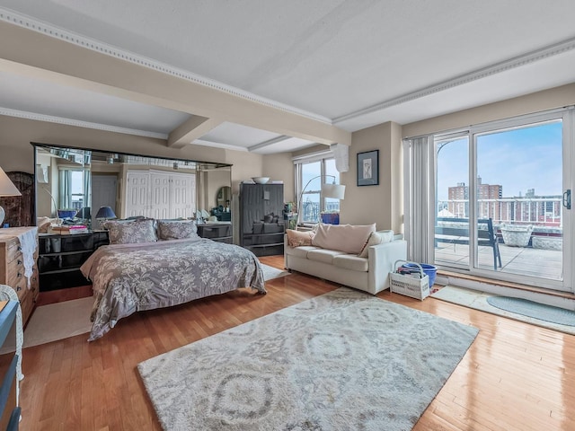 bedroom with access to exterior, a city view, beamed ceiling, wood finished floors, and coffered ceiling