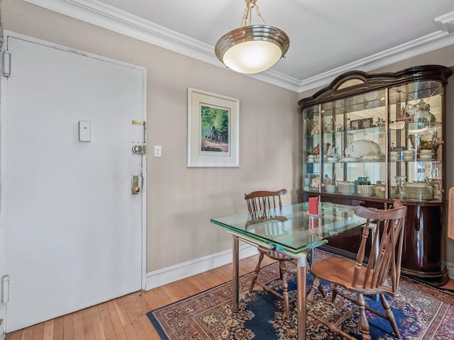 dining space with hardwood / wood-style floors, baseboards, and ornamental molding