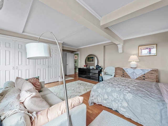 bedroom featuring beamed ceiling, wood finished floors, and ornamental molding