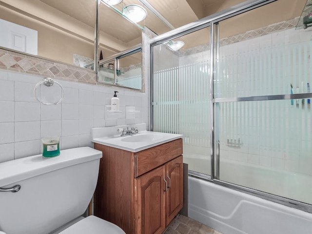 full bath featuring toilet, combined bath / shower with glass door, tile walls, decorative backsplash, and vanity