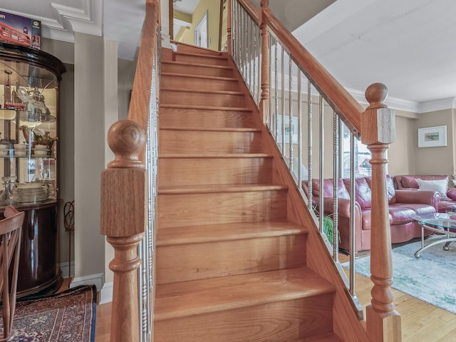 stairs featuring crown molding and wood finished floors