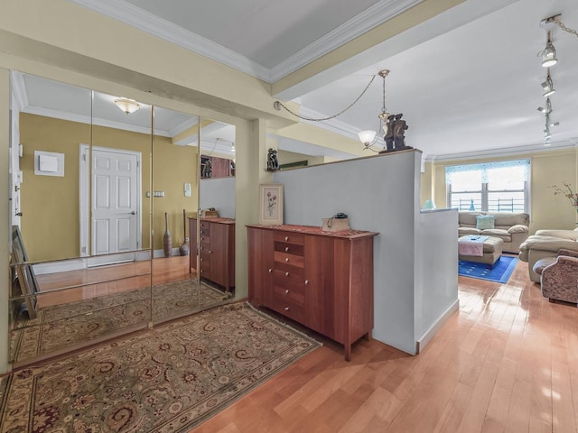 foyer entrance with a notable chandelier, track lighting, ornamental molding, and wood finished floors