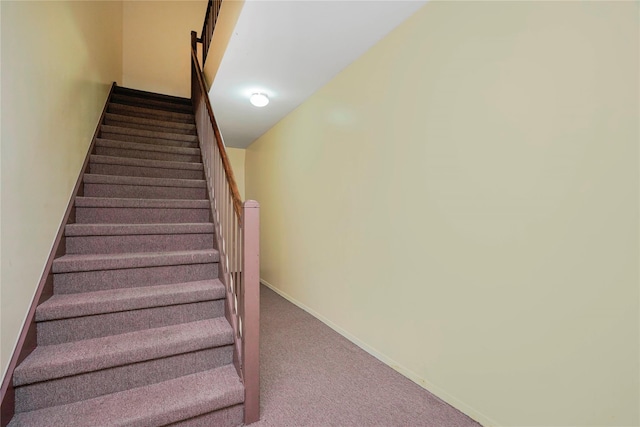 staircase featuring baseboards and carpet