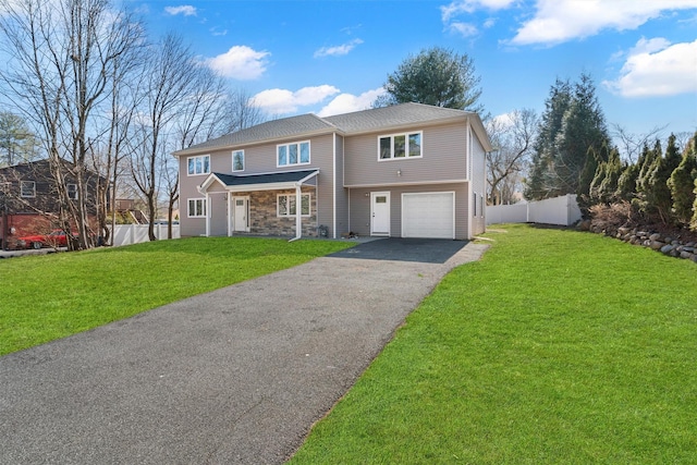 view of front of property with fence, driveway, a front lawn, stone siding, and a garage