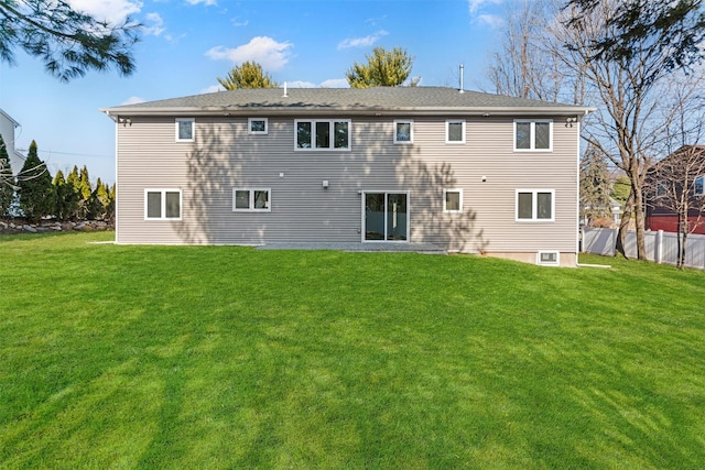 rear view of house featuring a yard and fence