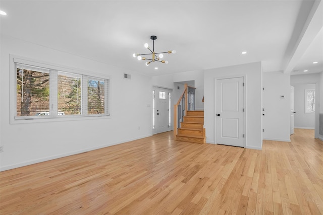 unfurnished living room featuring baseboards, an inviting chandelier, light wood-style flooring, recessed lighting, and stairs