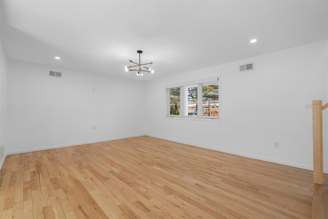 empty room with a notable chandelier, light wood-style floors, visible vents, and baseboards