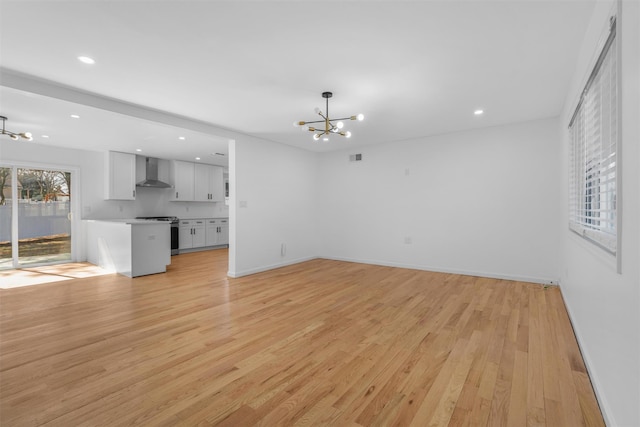 unfurnished living room with light wood finished floors, visible vents, baseboards, a chandelier, and recessed lighting