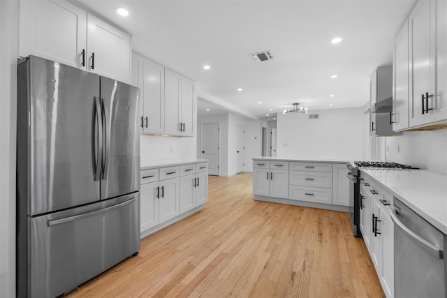 kitchen with light wood finished floors, visible vents, under cabinet range hood, light countertops, and appliances with stainless steel finishes