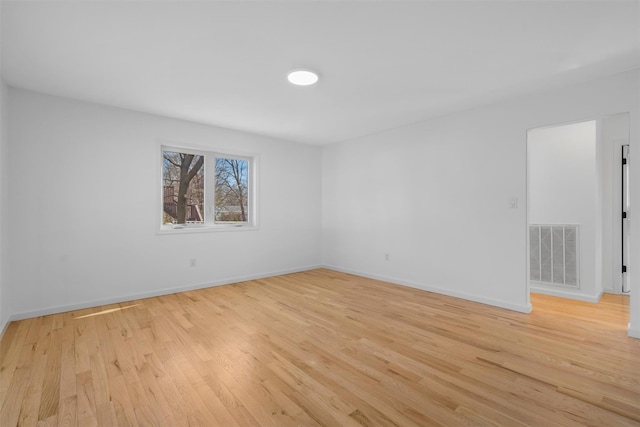 empty room with visible vents, light wood-style flooring, and baseboards