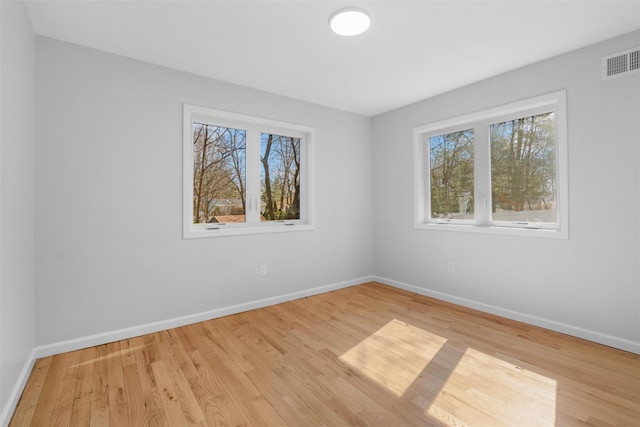 empty room featuring visible vents, baseboards, and wood finished floors