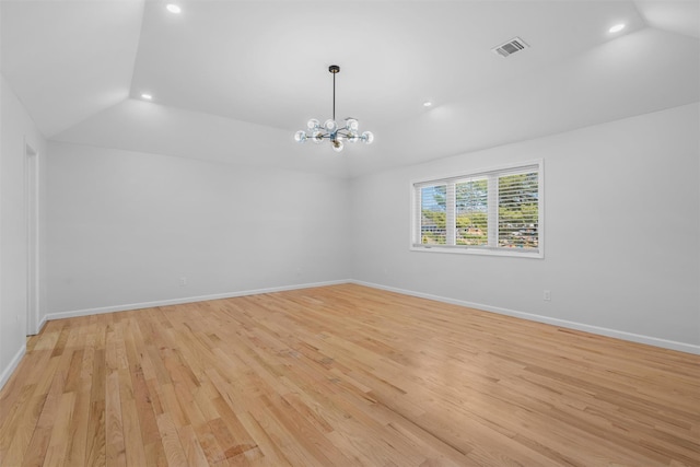 spare room featuring visible vents, baseboards, vaulted ceiling, light wood-style floors, and a notable chandelier