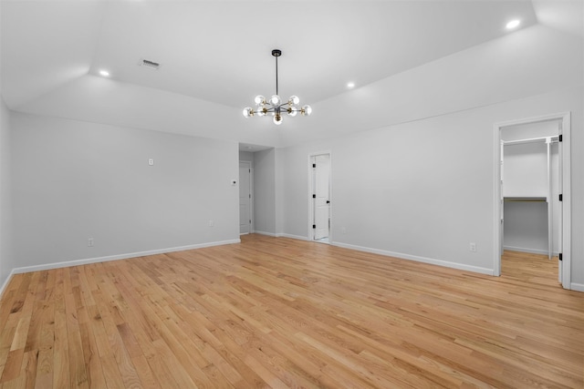 spare room featuring light wood-type flooring, visible vents, a notable chandelier, baseboards, and vaulted ceiling