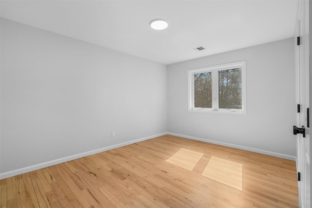 empty room with visible vents, baseboards, and wood finished floors