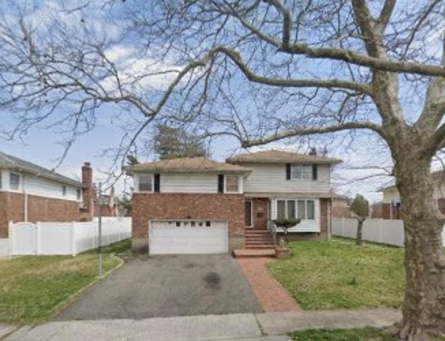 tri-level home with aphalt driveway, a front lawn, a garage, and fence