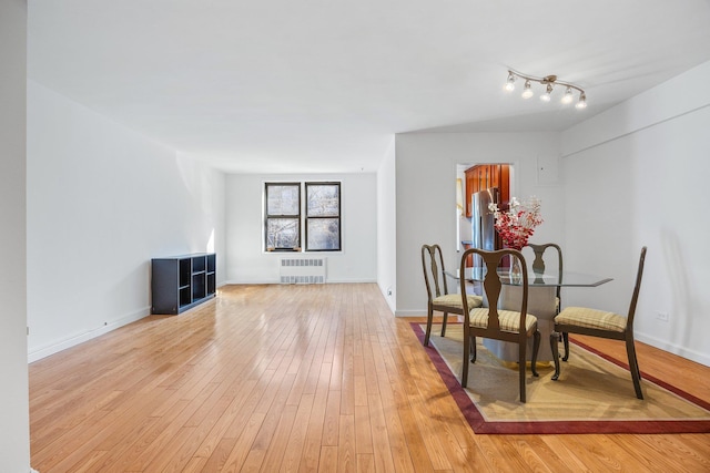 dining space with baseboards, radiator heating unit, and light wood-style floors