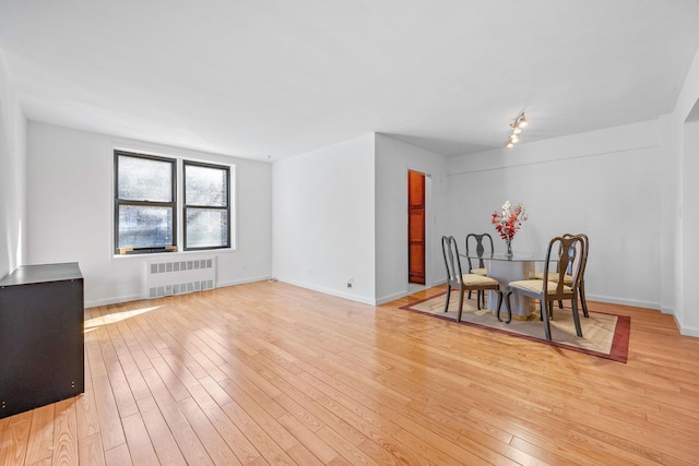 dining area with light wood-style floors, baseboards, and radiator