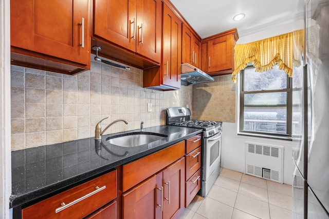 kitchen featuring under cabinet range hood, stainless steel range with gas stovetop, radiator heating unit, light tile patterned flooring, and a sink