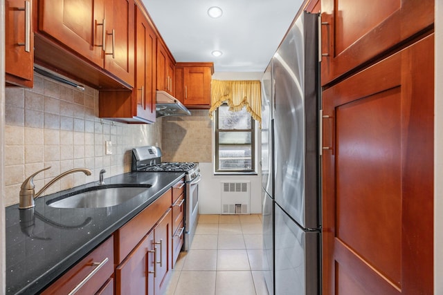 kitchen featuring tasteful backsplash, under cabinet range hood, light tile patterned floors, stainless steel appliances, and a sink