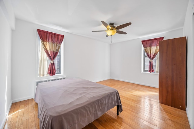 bedroom with ceiling fan, light wood-type flooring, and baseboards