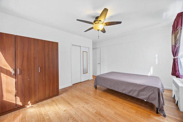 bedroom with light wood-style flooring, radiator, and a ceiling fan