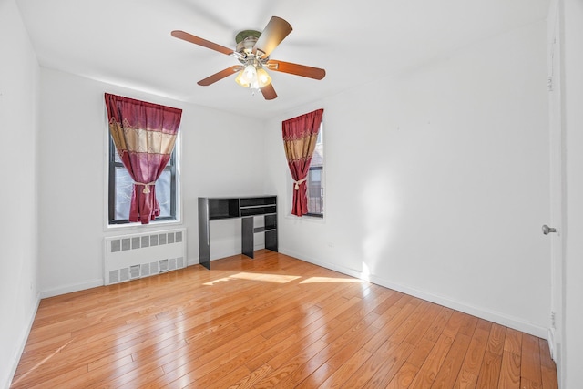 interior space featuring radiator, baseboards, light wood finished floors, and ceiling fan