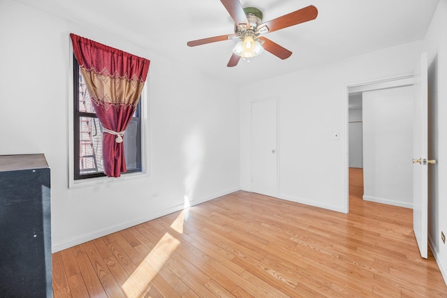 spare room featuring baseboards, light wood-type flooring, and ceiling fan