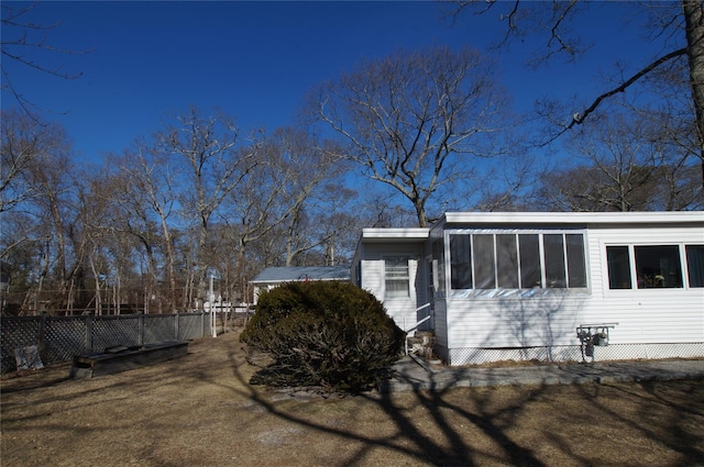 view of side of property with a sunroom and fence