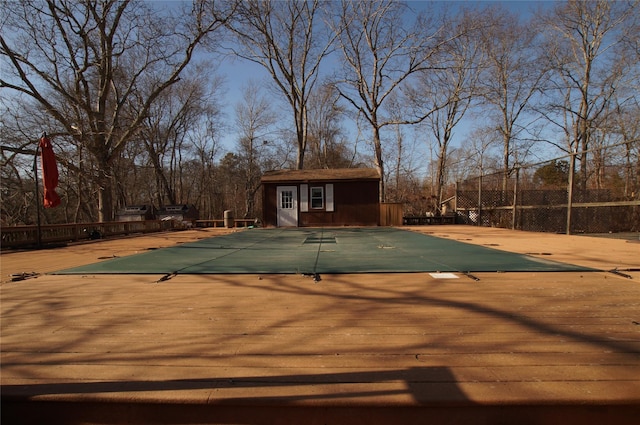 view of swimming pool featuring an outbuilding, a storage structure, and fence