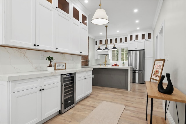 kitchen featuring light wood-style flooring, ornamental molding, a sink, wine cooler, and stainless steel fridge