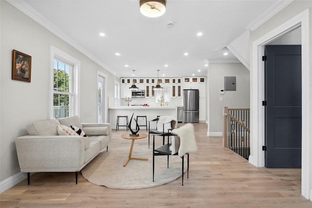 living area featuring electric panel, recessed lighting, light wood-style flooring, and crown molding