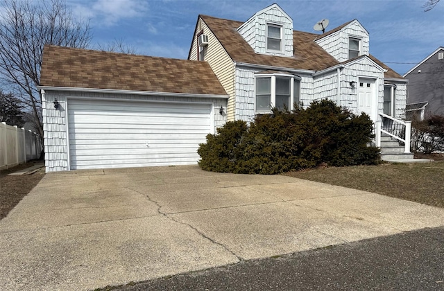 cape cod house with concrete driveway, an attached garage, and a shingled roof