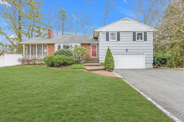 tri-level home with a front lawn, fence, an attached garage, a sunroom, and a chimney