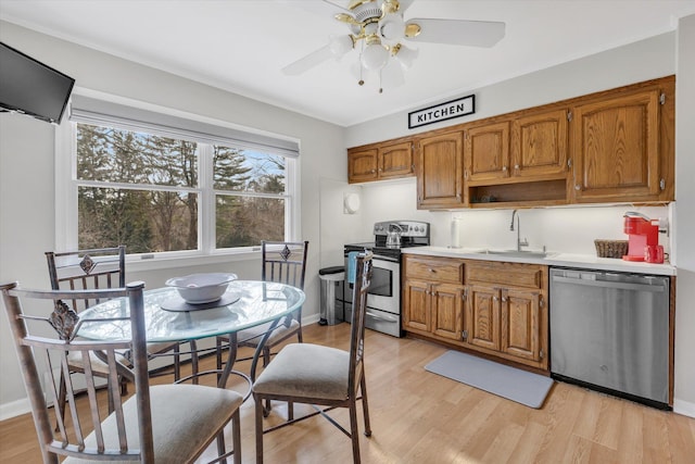 kitchen with a sink, brown cabinetry, light wood-type flooring, and stainless steel appliances