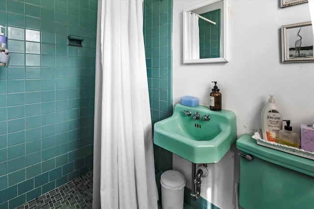 bathroom with a tile shower and a sink