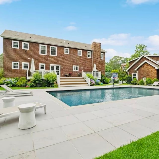 outdoor pool with a patio area and a wooden deck